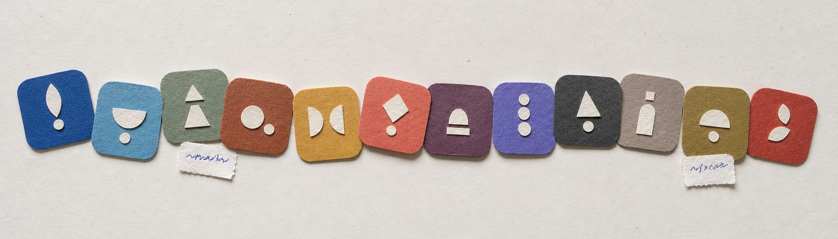 Twelve small paper app-icon squares in twelve flat colours, cut out and arranged loosely, a few overlapping.
